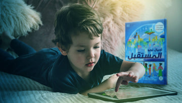 طفل يستخدم جهاز لوحي بينما يترك كتابًا تعليميًا بجانبه في مشهد يعكس هيمنة المحتوى الرقمي على تعلّم الأطفال